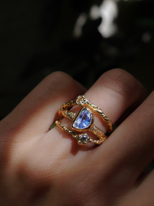 In Orbit Art Ring — worn in a gemstone ring stack against a dark background.