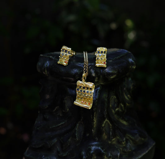 Tabula Rasa Earrings — earrings and matching pendant styled together on a dark sculptural surface.