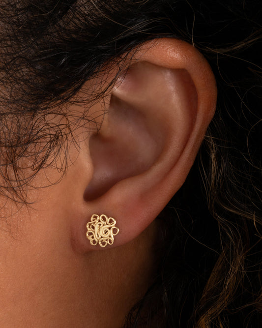 Lace Swirl Stud Earrings — one stud worn on an ear.