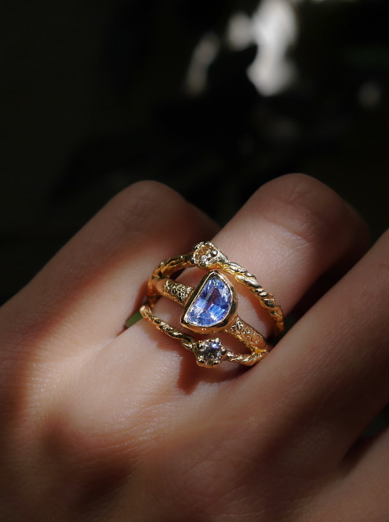 In Orbit Art Ring — worn in a gemstone ring stack against a dark background.