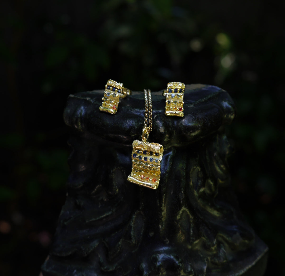 Tabula Rasa Pendant — pendant and matching earrings styled together on a dark sculptural surface.