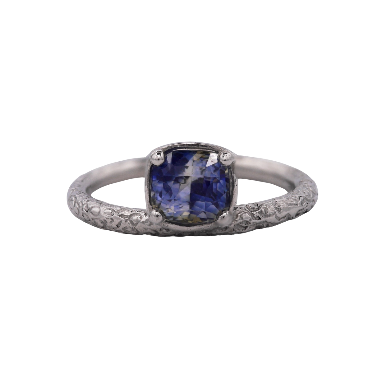 Aurora Ring — front view of a cushion sapphire in a four-prong setting above a scrolling band.