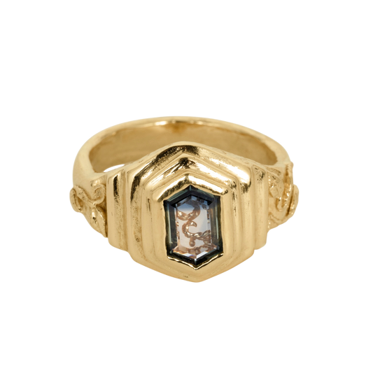 Curio Ring — A yellow-gold-colored signet ring centers a pale-blue elongated hexagonal sapphire in a raised bezel.