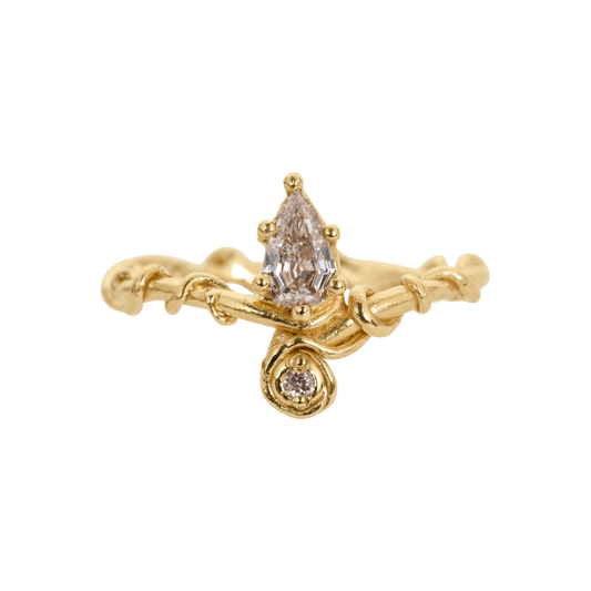 Diadem Diamond Ring — An asymmetric yellow-gold-colored ring pairs a large pear diamond with a smaller round diamond in a sculptural two-stone composition.