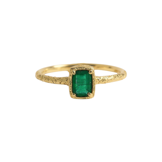 Emerald Script Ring — A rectangular green emerald is held by four prongs above a slender, scrolling yellow-gold-colored band.