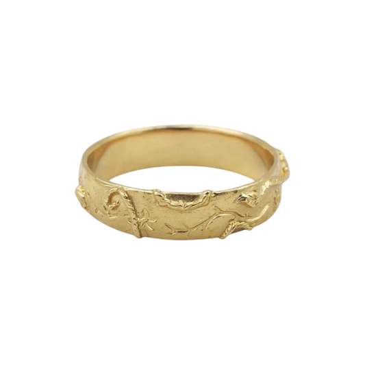 Gold Evergreen Ring — A wide yellow-gold-colored band is covered with raised branch and foliage relief.