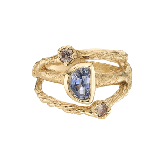 In Orbit Art Ring — An open yellow-gold-colored statement ring orbits one blue-violet asymmetric pear stone with two champagne round stones.