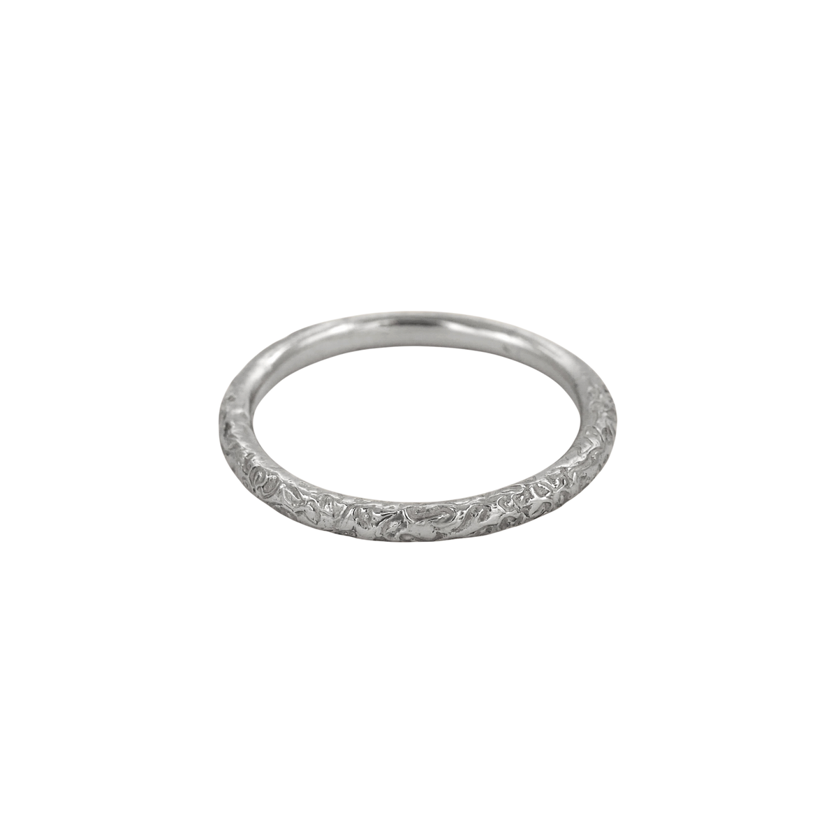 Little Scrolling Band Silver — A slim sterling-silver band carries shallow scrolling botanical relief around its rounded exterior.