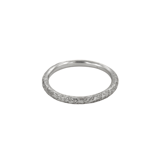Little Scrolling Band Silver — A slim sterling-silver band carries shallow scrolling botanical relief around its rounded exterior.