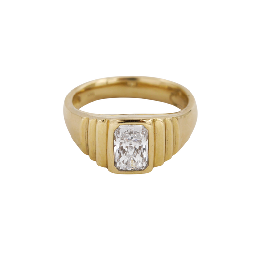 Meeting Place Ring — A colorless clipped-corner rectangular diamond is bezel-set in a polished, ridged yellow-gold signet ring.
