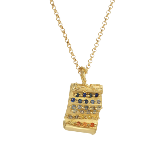 Tabula Rasa Pendant — A yellow-gold-colored scroll pendant carries 27 round multicolor sapphires in graduated horizontal rows beneath a carved leafy edge.