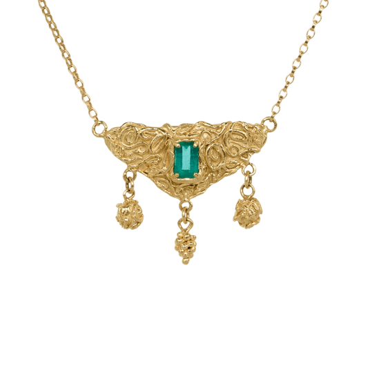 Utopia Necklace — An emerald-cut green emerald is prong-set in a triangular yellow-gold-colored centerpiece with open scrolling and three dangling sculptural drops.