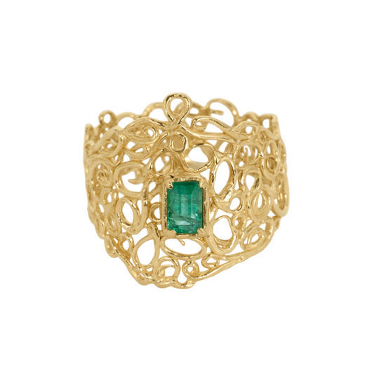 Utopia Ring — A green emerald-cut emerald is prong-set at the center of a wide yellow-gold-colored ring built from polished open scrollwork.