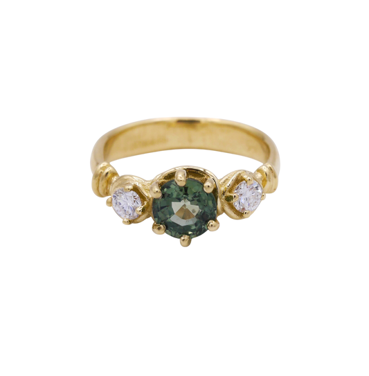 Verdant Ring — A round green sapphire is prong-set between two round colorless diamonds on a yellow-gold band with curled shoulder details.
