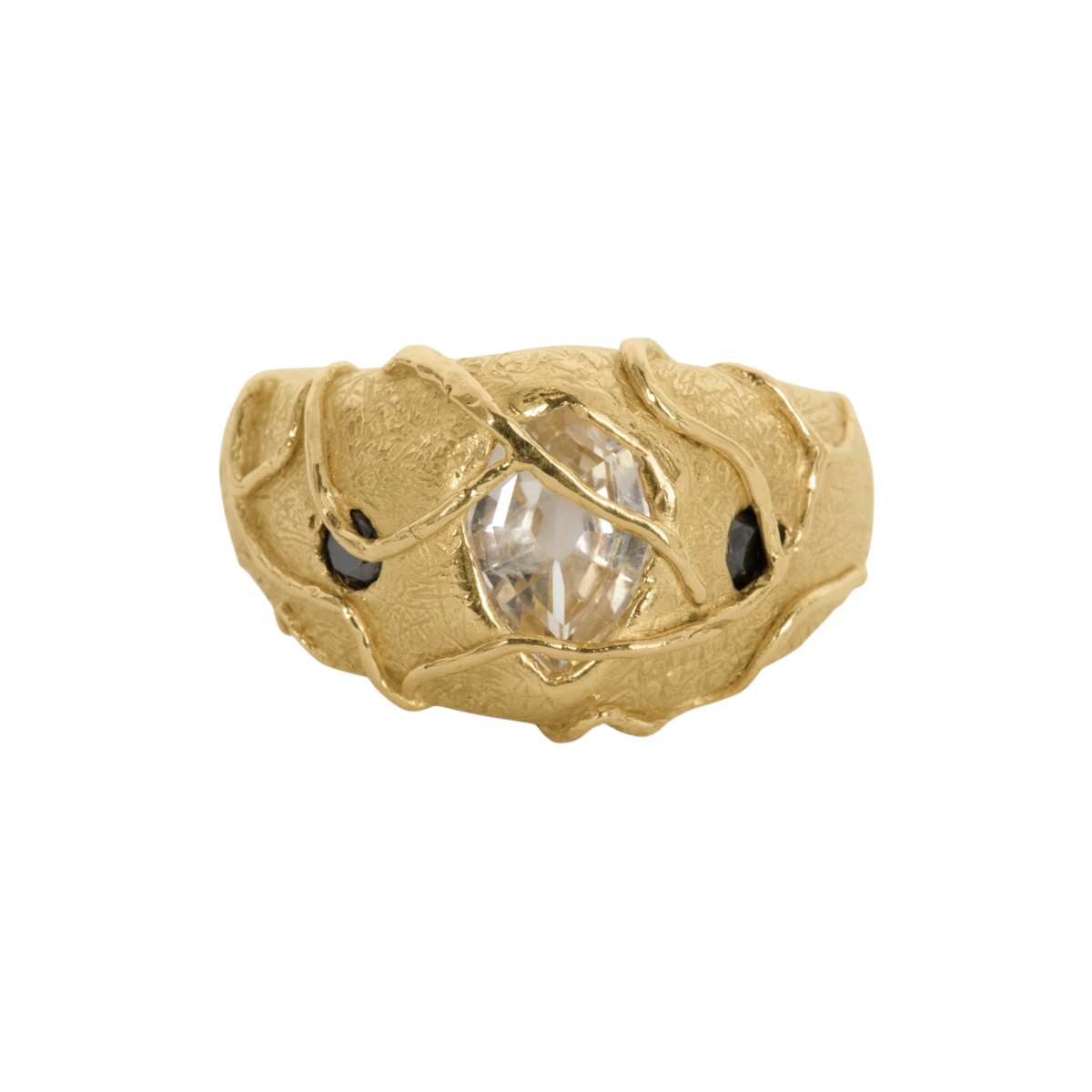 Watch Your Step Ring — A wide textured yellow-gold-colored ring holds one elongated colorless center stone and two small black pear-shaped side stones beneath crossing vine-like prongs.